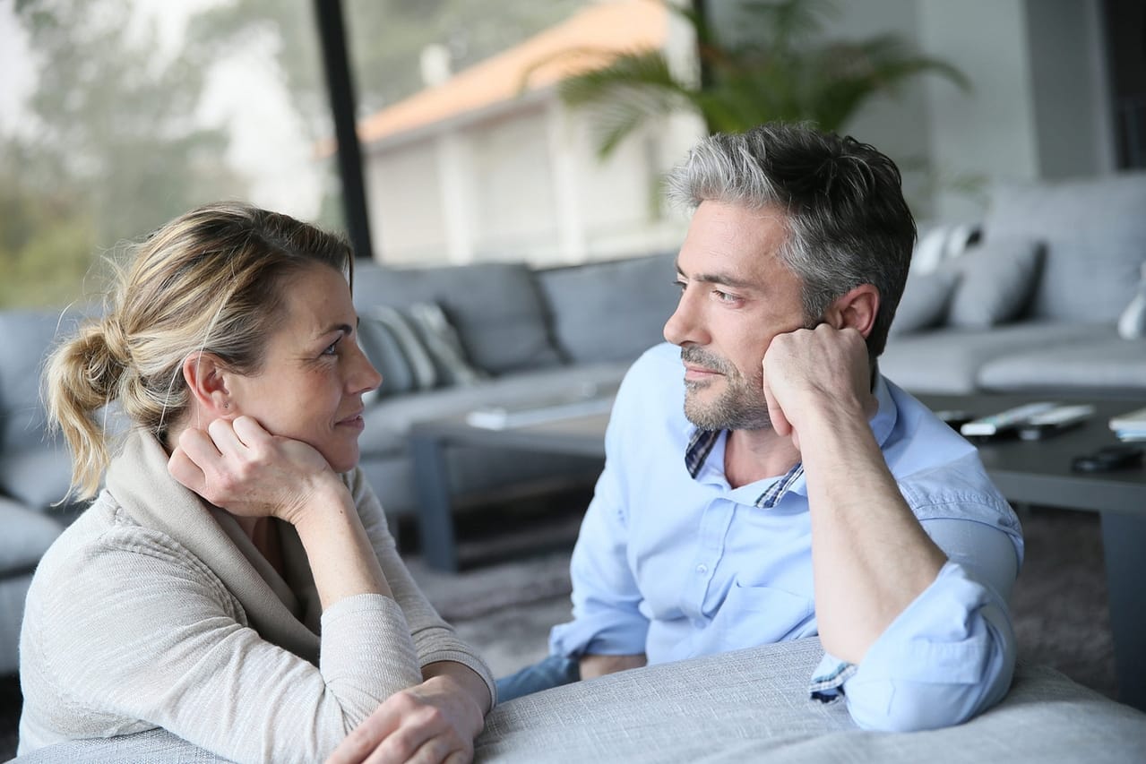mature couple talking to each other in sofa