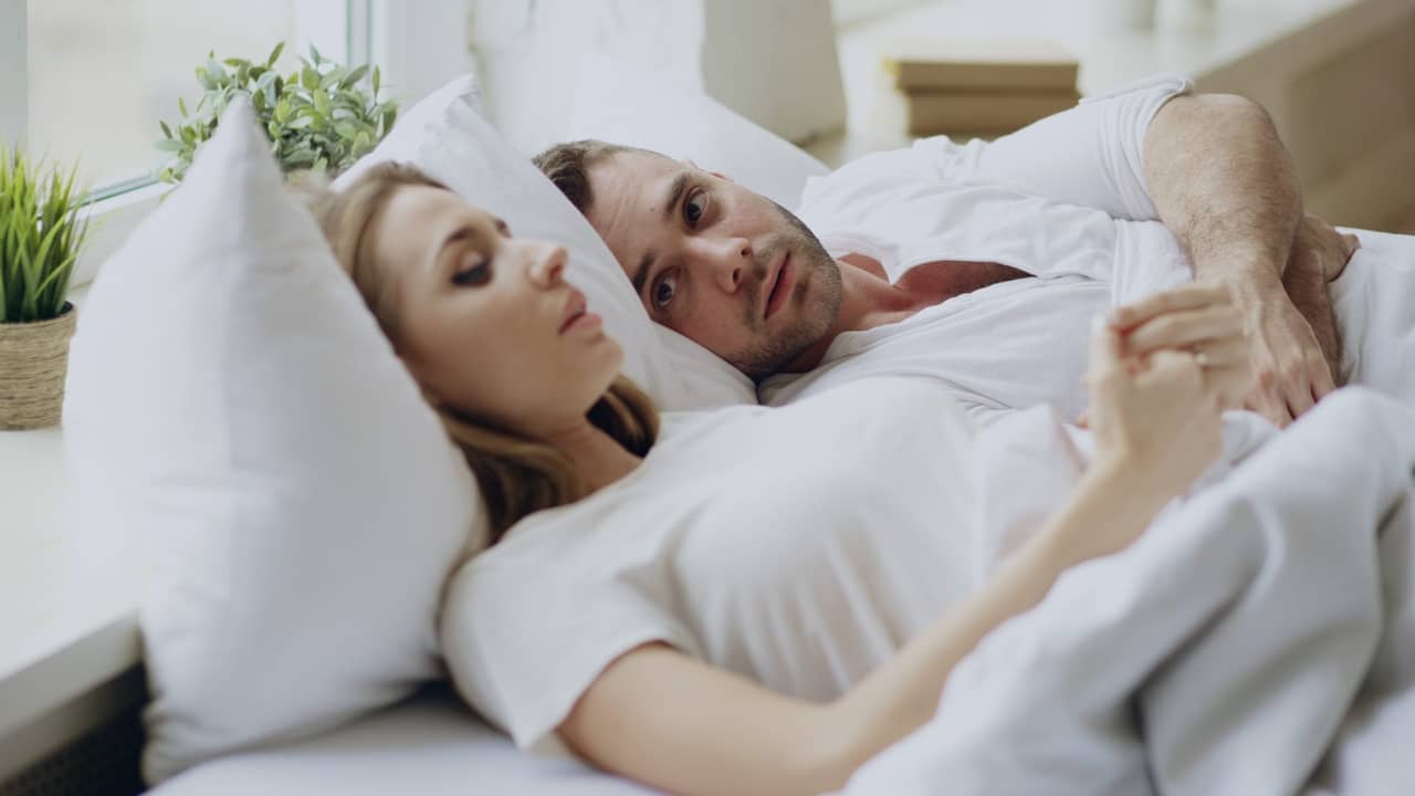 closeup of couple with relationship problems having emotional conversation while lying in bed at home