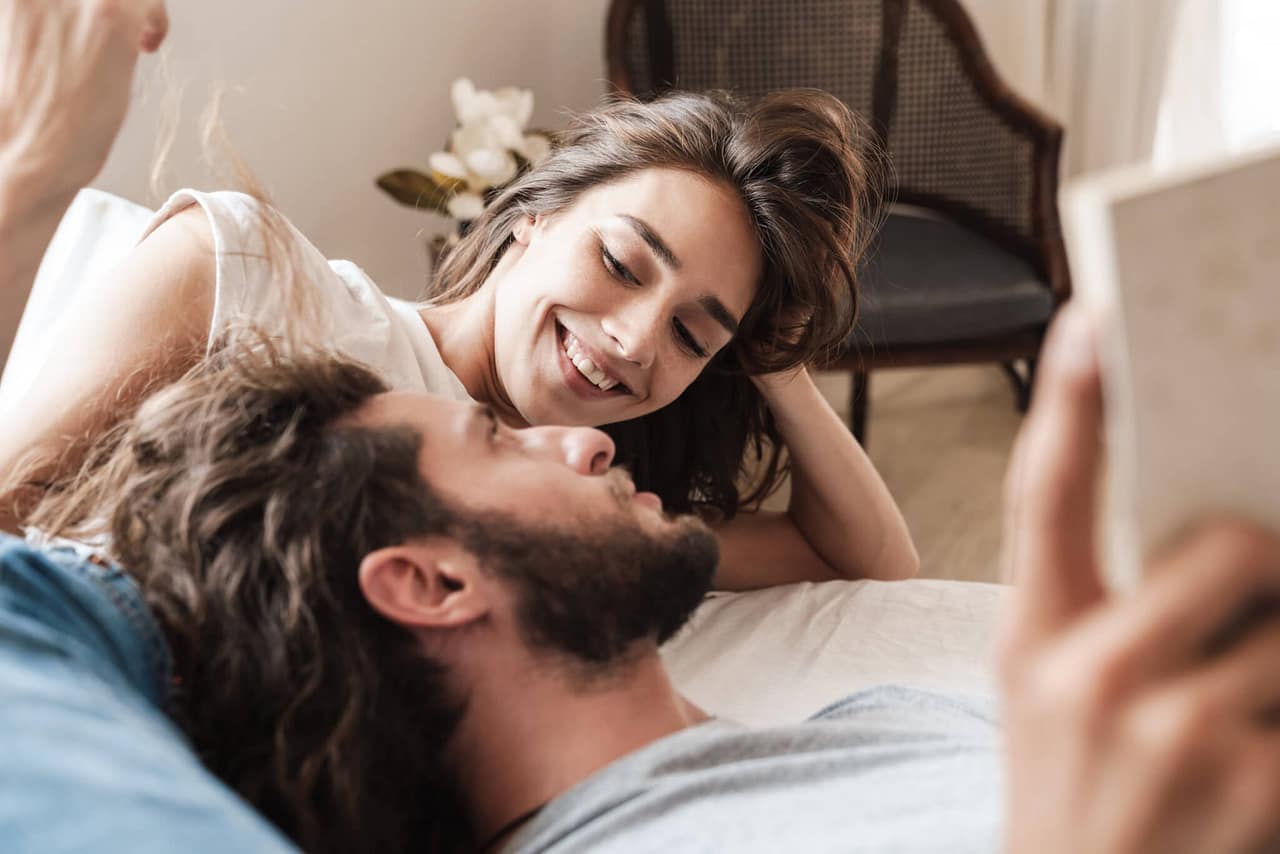 loving couple indoors at home lies reading book together