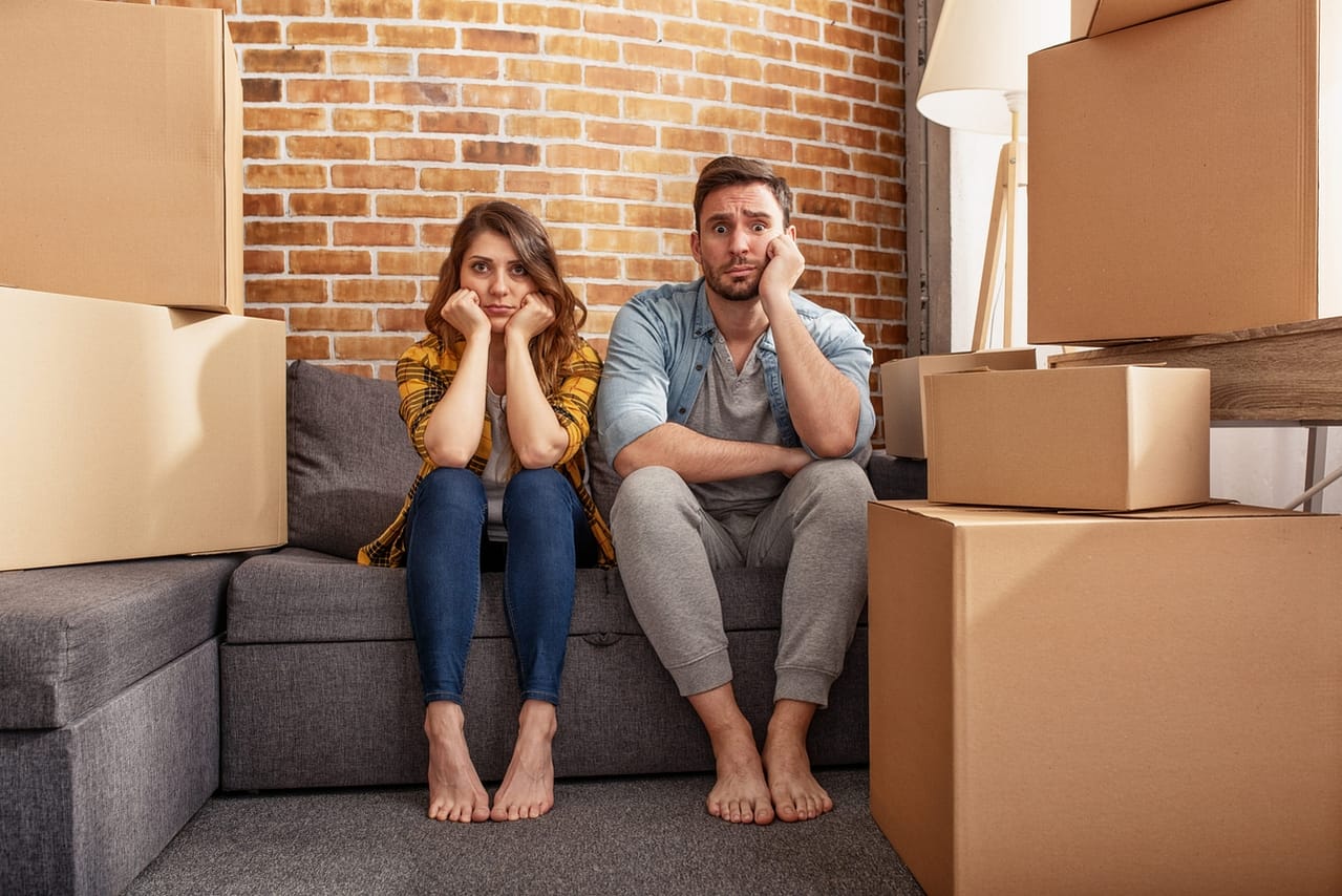 Zusammenziehen mit dem Partner in der Beziehung: So meistert ihr den neuen Lebensabschnitt! 1 confused couple of having to move and arrange all the packages concept of success delusion change and future